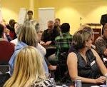 Large group discussion at a community engagement event with attendees seated in a conference room setting