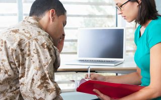 Military personnel receiving counseling from a professional in an office setting, focusing on mental health support