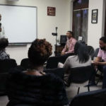 Speaker leading a wellness workshop for a diverse group of adults in a classroom-style setting."