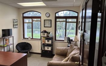 "Cozy wellness office with comfortable seating, natural light, and a serene view for client sessions and counseling."