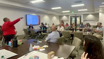 Facilitator leading an engaging workshop with participants seated at tables in a modern conference room